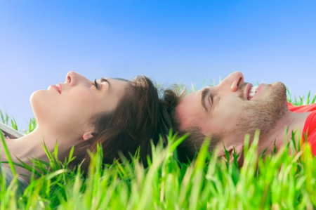 Young smiling couple lying down on the grass and dreaming at their futureの写真素材