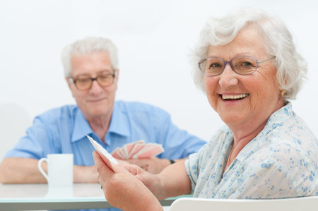 Happy smiling senior couple playing cards together at home