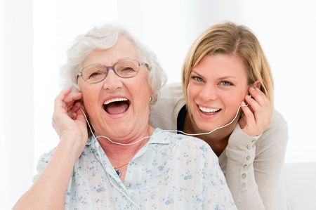 Super happy and excited grandmother listening music with her granddaughter at homeの写真素材