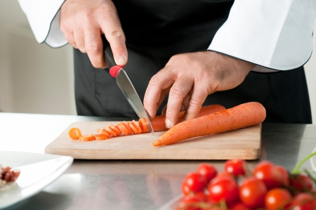 Cutting carrot on a wooden board for meal preparation at restaurantの写真素材