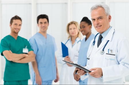 Portrait Of A Doctor and his colleagues With Medical Records