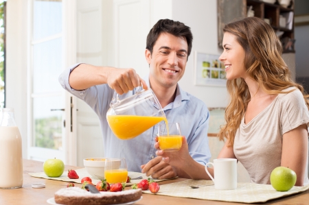 Portrait Of Happy Man Pouring Juice In Glass For Young Woman