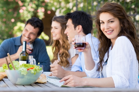 Happy Woman Holding Glass Of Wine With His Friends In Background Happy Woman Holding Glass Of Wine With His Friends In Background