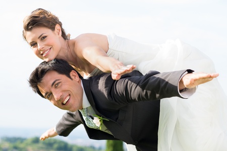 Happy Groom Giving Piggyback Ride To His Bride at Weddingの写真素材