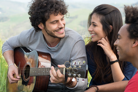 Young Man Looking At Woman While Playing Guitar Outdoorの写真素材