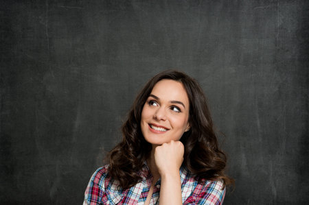 Happy Young Woman Contemplating Over Gray Backgroundの写真素材