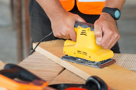 Closeup Of Carpenter Hand Sanding Plank With Electrical Sanding Machine