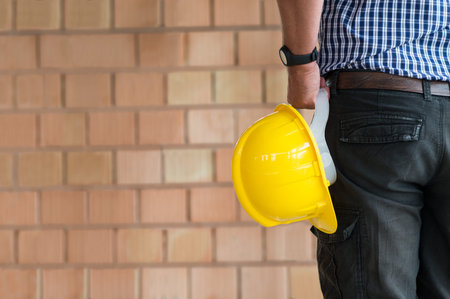 Close up Of Male Architect Holding Yellow Helmet At Construction Site