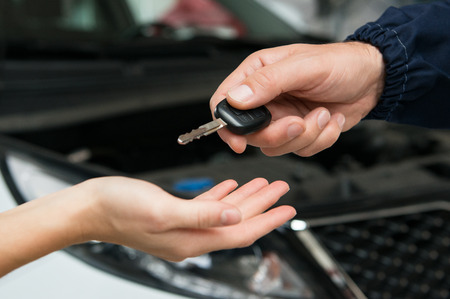 Closeup Of Mechanic Giving Car Key To Customer At Garageの写真素材