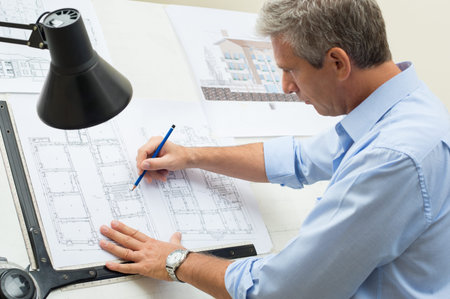 Portrait Of Male Architect Working On Blueprint At Office