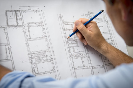 Closeup Of Male Architect Working On Blueprint At Office.
