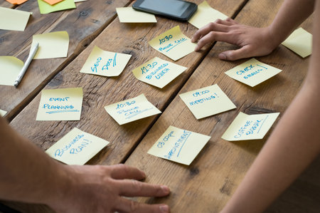 Businessman and woman leaning on desk with various sticky note papers