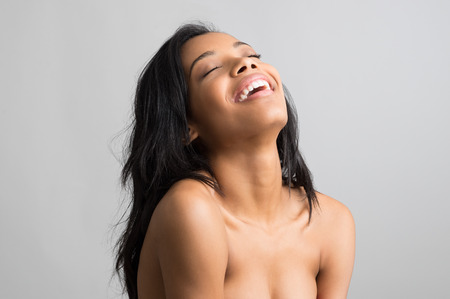 Beauty portrait of happy young african woman with eye closed isolated on grey backgroundの写真素材