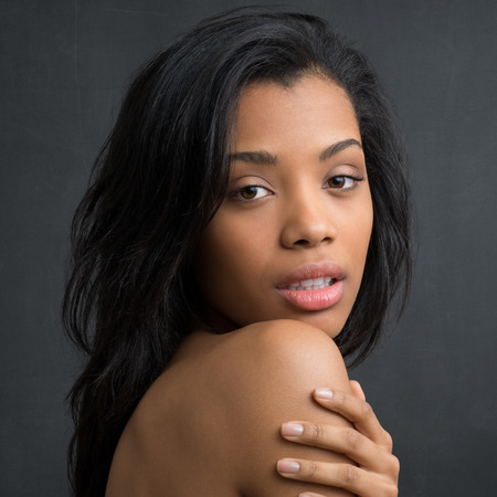Closeup of young african woman looking at camera over her shoulderの写真素材