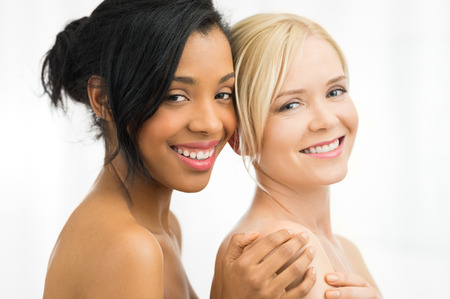 Closeup of beautiful young african and caucasian woman looking at camera  isolated on white backgroundの写真素材