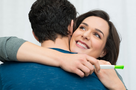 Closeup of happy young woman embracing man after positive pregnancy testの写真素材