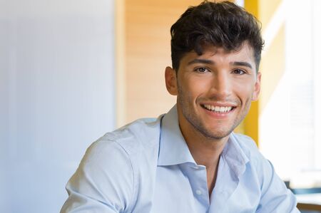 Closeup shot of young man smiling. Smiling guy with shirt looking at camera. Portrait of happy young man with beard indoor.の写真素材