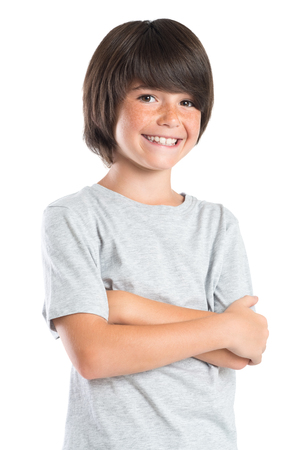 Portrait of a little boy standing with armcrossed. Studio portrait of happy male kid looking at camera. Smiling cute child with grey t-shirt laughing isolated on white background.の写真素材