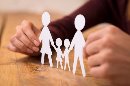 Close up of hands of a man and woman holding paper chain family. Young couple deciding on life after marriage. Closeup view of white paper cut family holding between hands.の写真素材