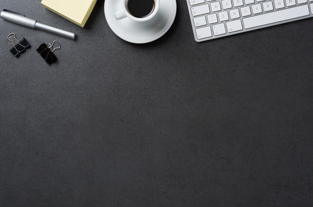High angle view of office black desk with copy space. Table with keyboard, computer, coffee cup and supplies.の写真素材