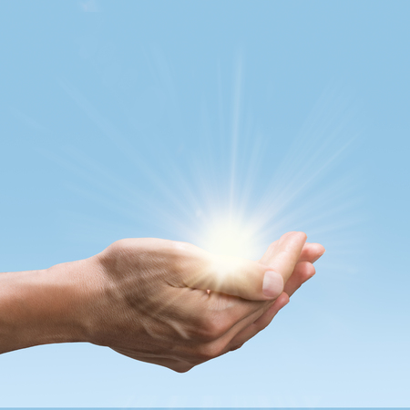 Close up of man hands holding a bright sun. Open palm gesture of male hand while hold the green energy of sun. Environmental conservation and green energy concept.の写真素材