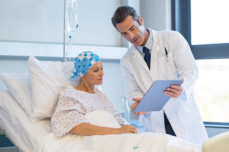 Doctor telling to patient woman the results of her medical tests. Doctor showing medical records to cancer patient in hospital ward. Senior doctor explaint the side effects of the intervention.の写真素材