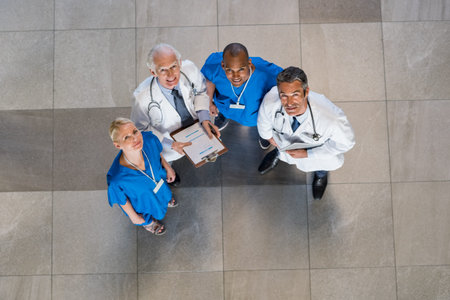 High angle view of doctors and nurses looking at camera during a conference. Cheerful nurses and...