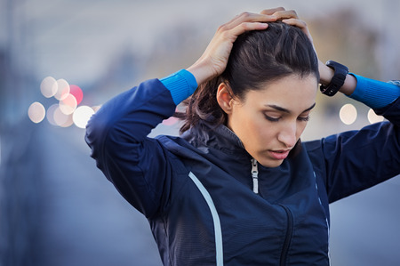 Young runner taking a break from jogging while holding head and breathing outdoor.の写真素材