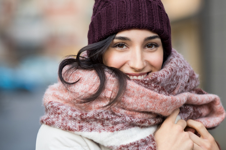Closeup face of a young happy woman enjoying winter wearing scarf and cap.の写真素材