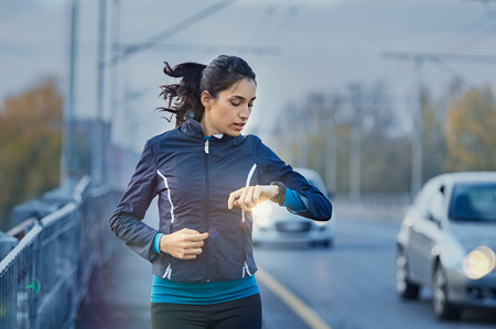 Young fitness woman runner checking time from smart watch.