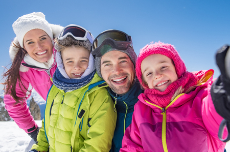 Happy family taking selfie in snowy mountain during winter holiday.の写真素材