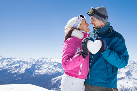 Young couple looking at each other and holding snow heart.の写真素材