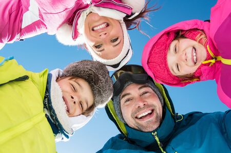 Smiling family with heads in a circle looking at camera in winter holiday.の写真素材