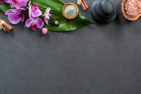 Top view of spa setting with hot stones, orchids and pink salt. High angle view of orchids with green leaf on blackboard with stacked hot stone for massage treatment. Luxury and elegant spa set with copy space.の写真素材