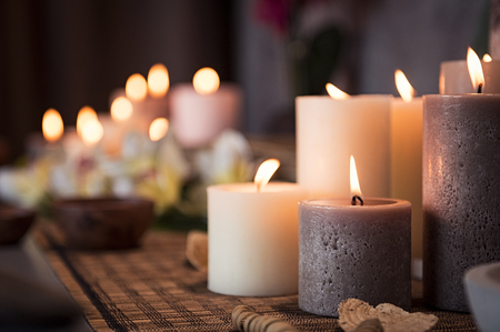 Closeup of burning candles spreading aroma on table in a spa room. Beautiful composition with grey and white candles for spa treatment. Zen and relax concept.の写真素材