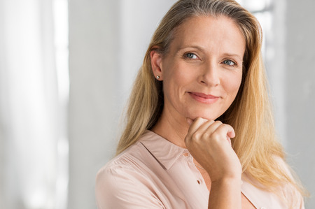 Portrait of a senior woman thinking with hand on chin and looking away. Mature smiling woman feeling happy. Thoughtful retired woman planning her future. Vision concept.の写真素材