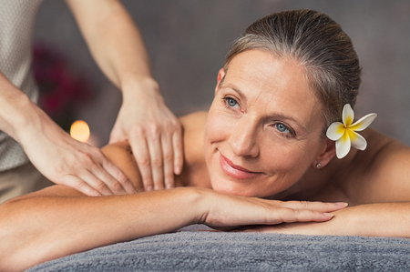 Senior woman in spa salon getting massage. Closeup of a beautiful woman during spa treatment. Beautiful mature woman receiving massage of shoulder at beauty salon.の写真素材