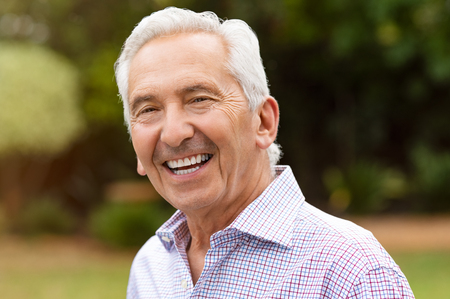 Portrait of a cheerful old man outdoor. Smiling retired man looking at camera. Senior grandfather enjoying life after retirement at park.の写真素材