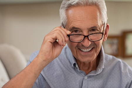 Portrait of happy mature man wearing spectacles and looking at camera. Old man smiling with glasses at home. Closeup face of elder trying new eyeglasses.の写真素材