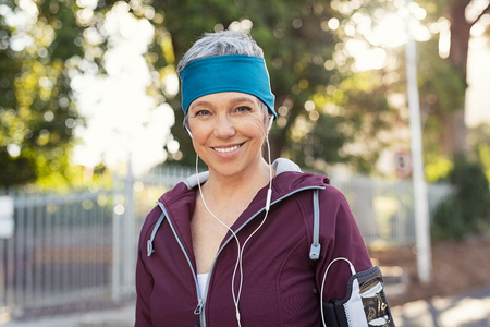 Portrait of smiling senior woman listening to music after running.の写真素材