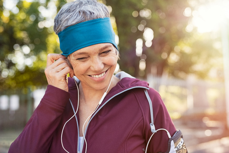 Portrait of smiling senior woman listening to music after running.の写真素材