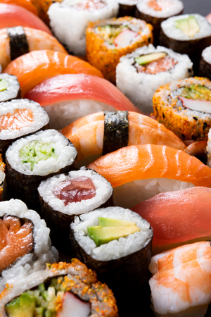 Variety of sushi food. Top view of nigiri, maki, hosomaki, uramaki and roll with tuna, salmon, avocado and shrimp. Traditional asian food with raw fish and rice. All you can eat concept.の写真素材