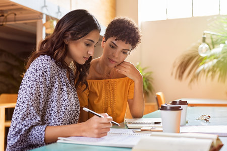 Young multiethnic women studying together at library. High school or college students studying and...