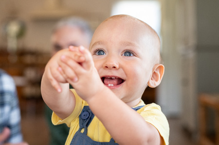 Excited toddler looking up with extended hands. Cute little boy showing hands and playing at home. Closeup face of happy smiling baby enjoying playing alone while looking away.の写真素材