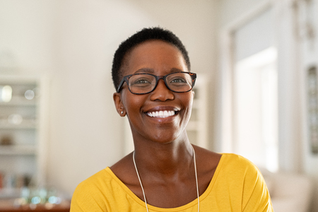 Portrait of young woman at home wearing spectacles. Beautiful mature woman wearing eyeglasses and looking at camera. Cheerful african american lady with glasses and short hair.の写真素材