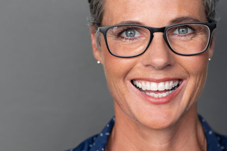Portrait of happy mature woman wearing eyeglasses and looking at camera. Closeup face of smiling...