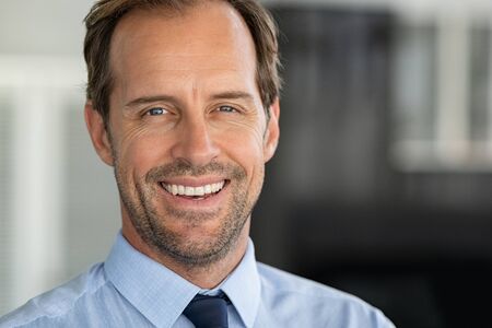 Portrait of mature businessman smiling. Close up face of happy successful business man looking at camera with copy space. Close up shot of cheerful satisfied leader face.の写真素材