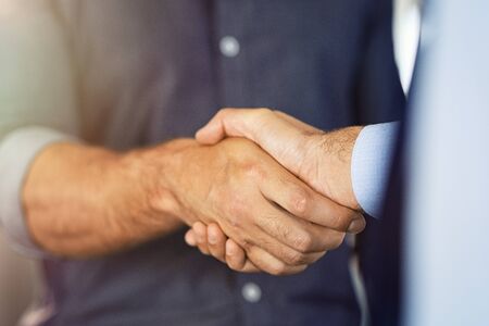 Close up of friendly handshake of business people. Business partners signing deal with handshake at office. Negotiation meeting for a successful merger, business agreeement.の写真素材