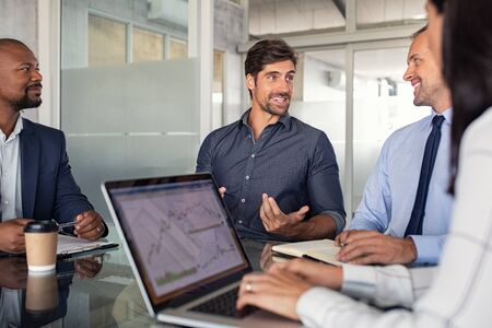 Group of business people discussing financial matter during meeting. Team of business partners at work in office. Businessmen and businesswoman sitting at conference table in front of laptop and working together.の写真素材