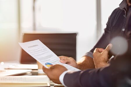 Businessman showing a document to his colleague. Businessman analyze graphs and charts with manager. Two businessmen reading business contract for merger and acquisition. の写真素材